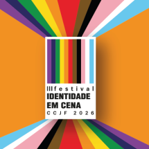 Cartaz do “III Festival Identidade em Cena – CCJF 2026”. Ao centro, um retângulo branco traz o nome do festival em letras pretas, atravessado por faixas verticais coloridas inspiradas nas cores da diversidade LGBTQIA+. Essas faixas se expandem para fora do cartaz em direção às bordas da imagem, formando composição vibrante sobre fundo laranja.