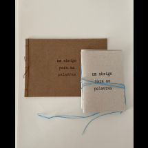 Fotografia de dois cadernos artesanais com capas em papel reciclado, posicionados sobre fundo claro. O maior, ao fundo, tem capa marrom e costura lateral com linha laranja. O menor, à frente, possui capa clara amarrada com barbante azul. Ambos trazem o título “um abrigo para as palavras” impresso em letras pretas, em composição simples e delicada.
