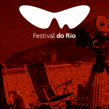 Arte do Festival do Rio, em tons de vermelho, laranja e preto, com o logotipo do evento em destaque. Ao fundo, cenário de praia com duas cadeiras voltadas para o mar, morro ao longe e uma câmera de cinema sobre tripé à direita.