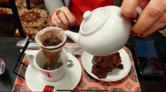 Bule de água quente preparando um café no coador de pano junto a um pedaço de bolo de chocolate