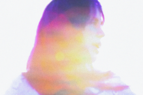 Cartaz do filme Apocalipse Segundo Baby. A imagem mostra o perfil de uma mulher voltada para a direita, envolto por um efeito de sobreposição de luzes e cores em tons de rosa, roxo, amarelo, laranja e azul. O rosto e o corpo aparecem suavizados e parcialmente desfocados, criando uma composição abstrata e onírica, em que a figura parece se dissolver em um halo de luz colorida.