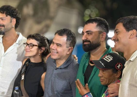 Parte da equipe do filme Papagaios posa reunida para uma fotografia. Seis pessoas aparecem lado a lado, sorrindo e abraçadas, em um ambiente externo durante a noite.
