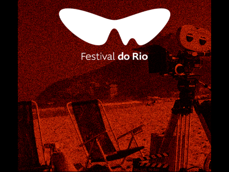 Arte do Festival do Rio, em tons de vermelho, laranja e preto, com o logotipo do evento em destaque. Ao fundo, cenário de praia com duas cadeiras voltadas para o mar, morro ao longe e uma câmera de cinema sobre tripé à direita.